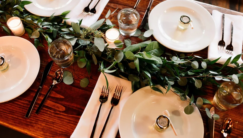 A white dinner plate placed on a brown wooden table, set for a meal.