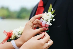 A girl pinning a flower to a boy’s suit.