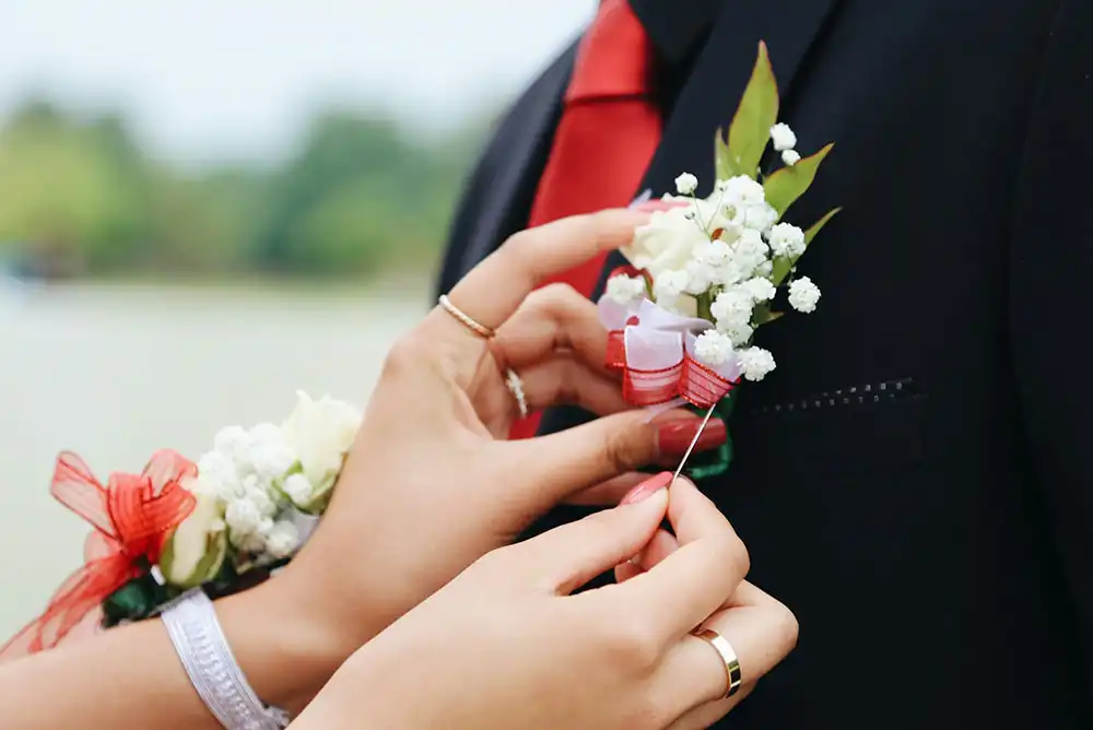 A girl pinning a flower to a boy’s suit.